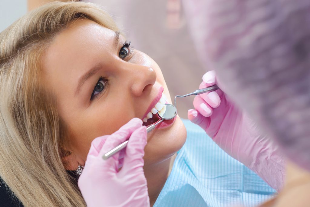 Young Dentist Working In Dental Clinic With Patient In The Chair